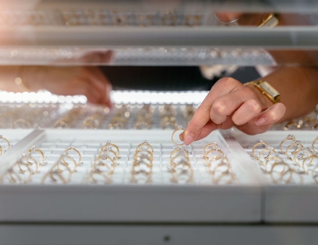 a jeweler’s hands retrieving an engagement ring from a display case