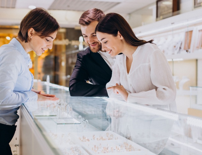 Two jewelers and a customer looking at a jewelry display case