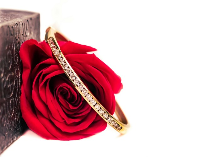 a red rose with a diamond ring looped around it