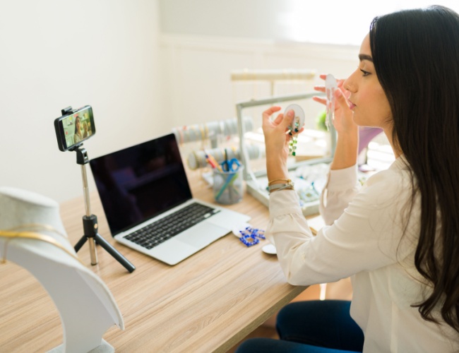 a lady wearing jewelry making a video of herself with her phone camera